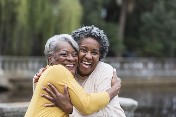 two elderly women friends hugging