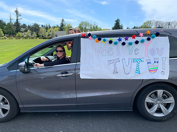 Van in a parade with a banner hanging off it's side