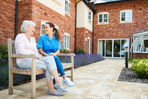 caregiver talking with senior woman on a bench