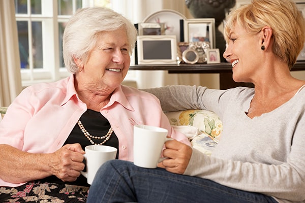 Senior woman and daughter drinking tea on a couch