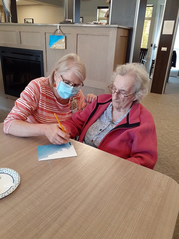 caregiver helping senior woman create a shopping list