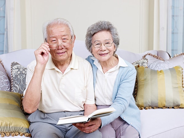 senior couple reading a book while smiling at the camera