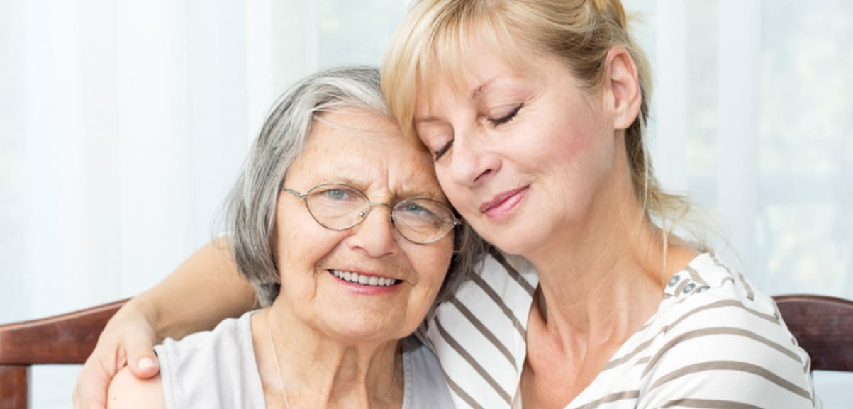 daughter comforting mother while wrapping her arm around her shoulders