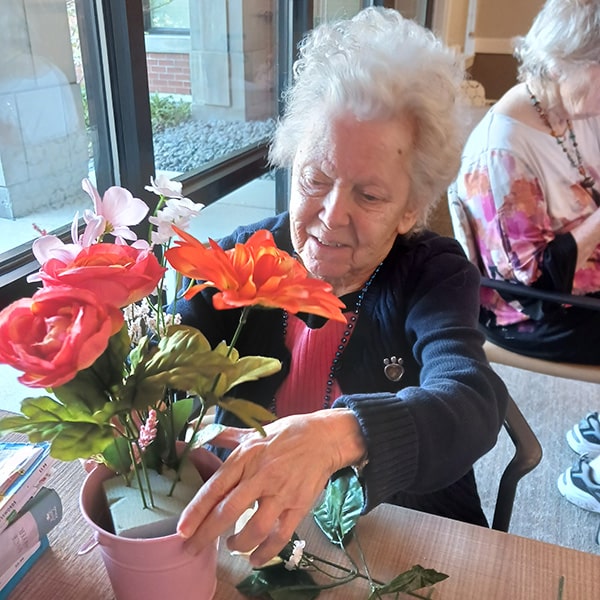 senior woman planting a flower in a pot