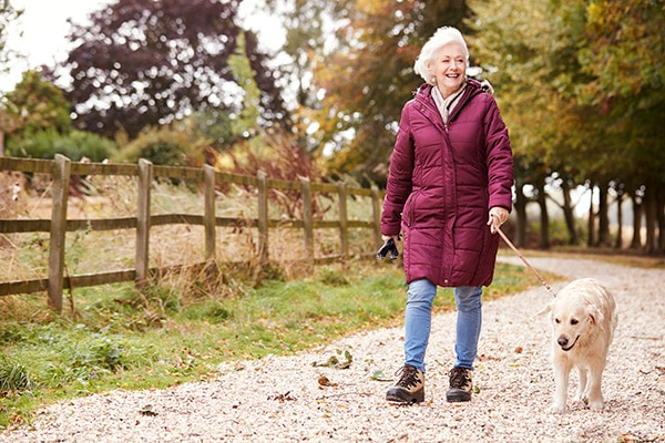 senior woman walking a dog in the park