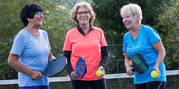 three senior women playing pickelball