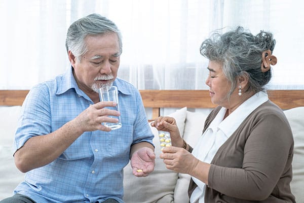 Woman giving elderly man his daily vitamins