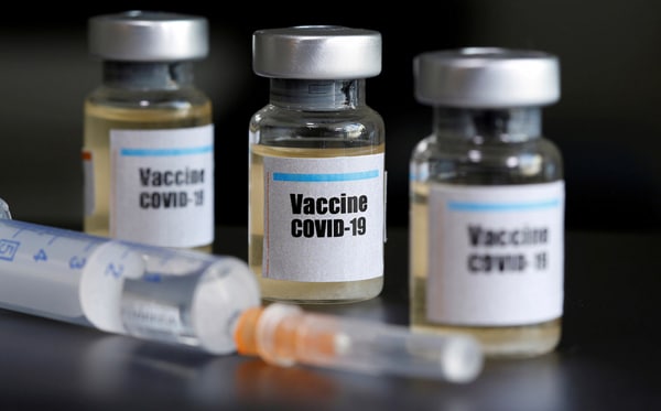 COVID-19 Vaccine vials with a needle in front.