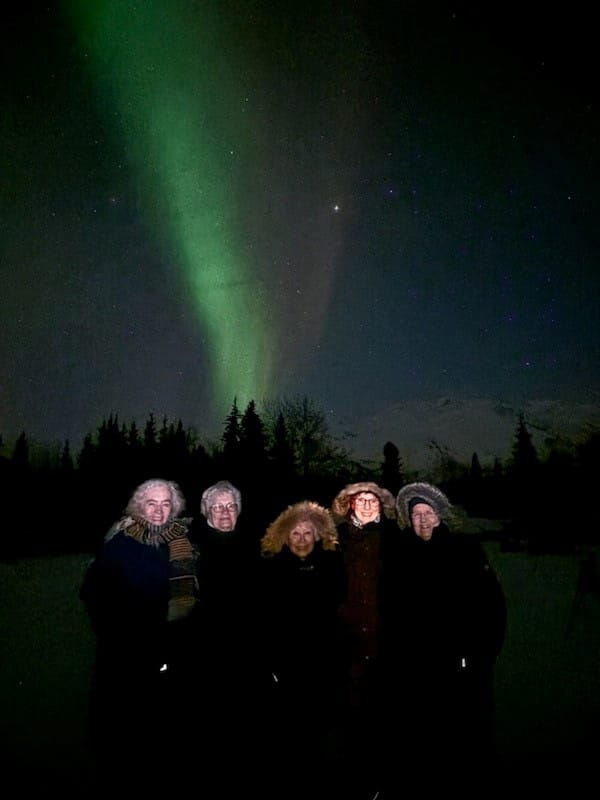 group of residents with the northern lights glowing n the background