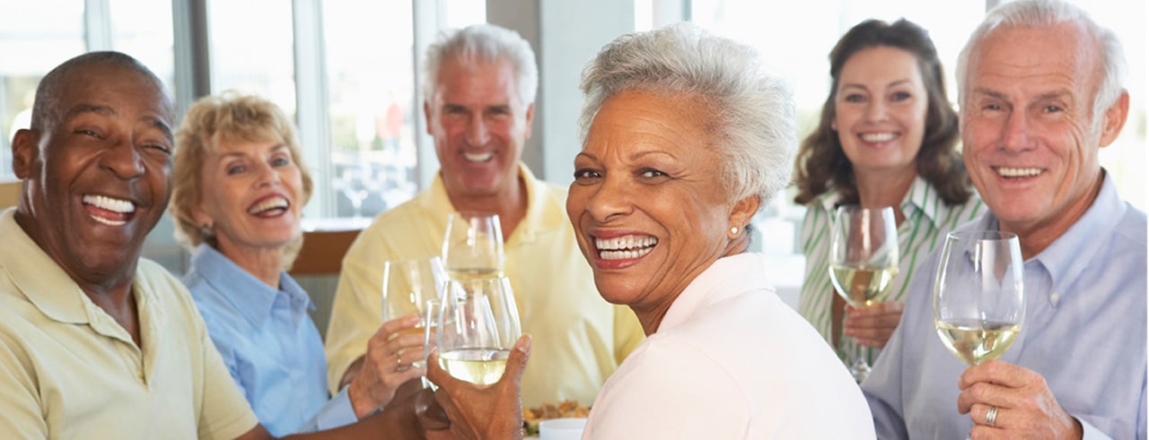 group of senior friends toasting glasses of white wine