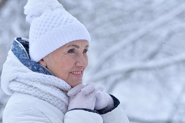 Senior woman outside in the snow, wearing a warm coat