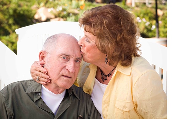 daughter gently kissing father on the head