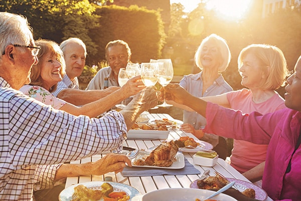 group of seniors enjoying a picnic outside in the sun