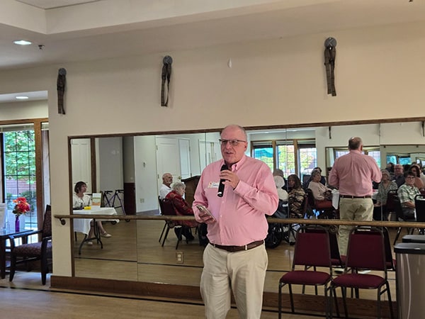 senior man speaks in front of room of donors
