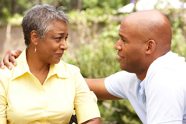 adult son talking with his senior mother on a bench outside
