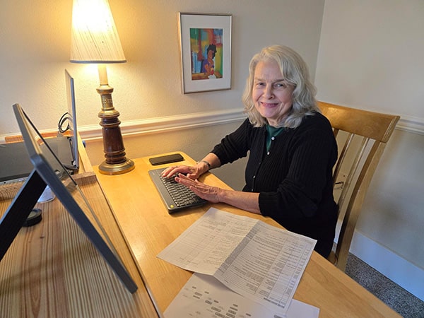 senior woman sitting at her desk and smiling at the caemra
